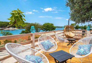 Modern deck with stylish chairs, cushions, and sea view at Camping Arena One 99 Glamping in Istria, Croatia.