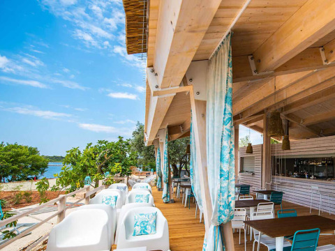 Outdoor dining area with sea view and wooden decor at Camping Arena One 99 Glamping, Istria, Croatia.
