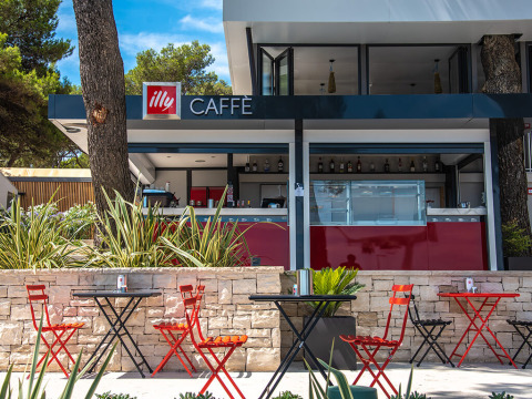 Outdoor café at Camping Arena One 99 Glamping in Istria, Croatia, featuring red chairs and black tables.