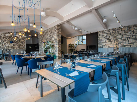 Interno ristorante moderno al Camping Arena One 99 Glamping, Istria, Croazia, con sedie blu e pareti in pietra.