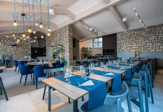 Interno ristorante moderno al Camping Arena One 99 Glamping, Istria, Croazia, con sedie blu e pareti in pietra.