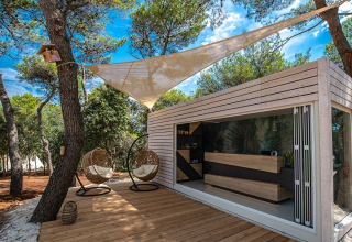 Lounge all’aperto moderna e reception al Camping Arena One 99 Glamping in Istria, Croazia, circondata da alberi.