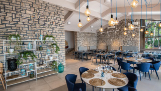 Moderne restaurantindretning med stenvægge, blå stole og ophængte pærer på Camping Arena One 99 Glamping i Istrien.