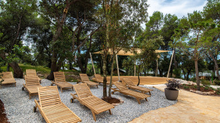 Afslapningsområde med træliggestole og skyggefulde træer på Camping Arena One 99 Glamping i Istrien, Kroatien.