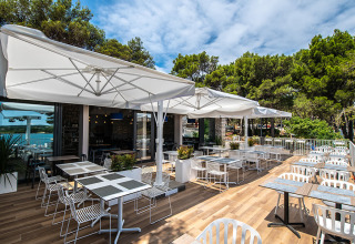 Terrazza esterna con tavoli e sedie moderne al Camping Arena One 99 Glamping in Istria, Croazia, vicino al bosco.