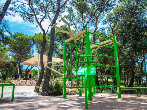 Outdoor fitness gym with green equipment surrounded by trees at Camping Arena One 99 Glamping in Istria, Croatia.