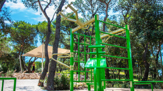 Udendørs fitnessområde med grønne fitnessredskaber under træer på Camping Arena One 99 Glamping i Istrien.