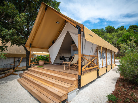 A luxurious glamping tent with a wooden terrace and hammock at Camping Arena One 99 Glamping in Istria, Croatia.