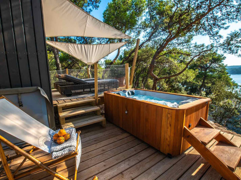 Bain à remous extérieur et terrasse boisée au Camping Arena One 99 Glamping en Istrie, Croatie.