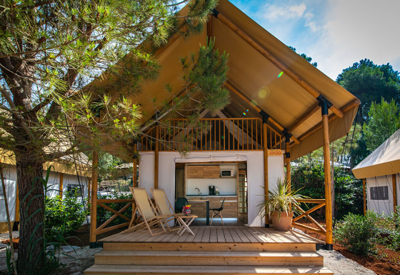Premium safaritent met twee slaapkamers bij Camping Arena One 99 Glamping in Kroatië, omgeven door bomen.