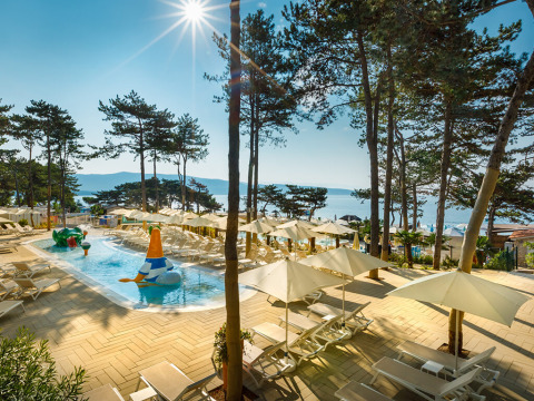 Piscine ensoleillée avec transats et parasols au Valamar Camping Ježevac, village vacances en Croatie en bord de mer.