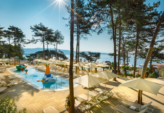 Zona piscina soleggiata con lettini e ombrelloni al Valamar Camping Ježevac, villaggio vacanze sul mare in Croazia.