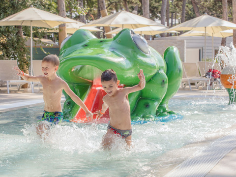 Due bambini giocano nella piscina per bambini davanti a uno scivolo a rana a Valamar Camping Ježevac, Croazia.