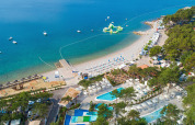 Vista aerea di Valamar Camping Ježevac in Croazia con spiaggia, piscine e parco acquatico galleggiante sul mare.