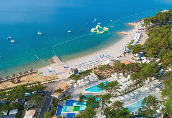 Luchtfoto van Valamar Camping Ježevac in Kroatië met strand, zwembaden en drijvend waterpark in zee.