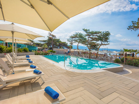 Outdoor pool area with sun loungers and umbrellas at Valamar Camping Ježevac, Primorje-Gorski Kotar, Croatia.
