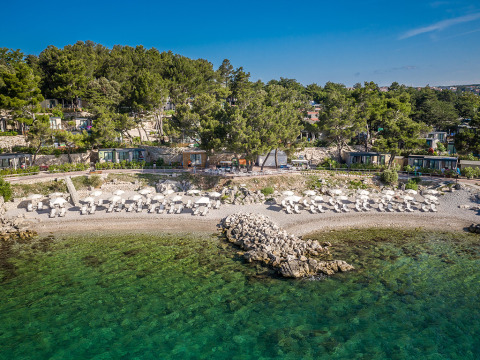 Vakantiepark Valamar Camping Ježevac in Primorje-Gorski Kotar, Kroatië, met strand en ligstoelen onder parasols.