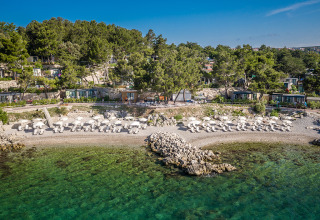 Valamar Camping Ježevac dans le comté de Primorje-Gorski Kotar, Croatie, avec plage, parasols et arbres verts.