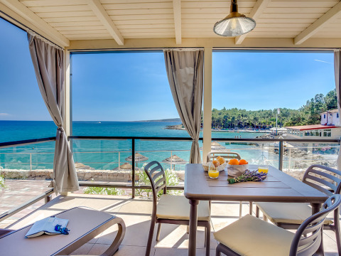 Overdekt terras met uitzicht op zee, eettafel en ligstoelen bij Valamar Camping Ježevac, Kroatië.