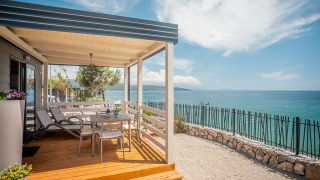 Terrazza in legno del Lungomare Chalet con vista mare spettacolare, lettini e zona pranzo coperta.