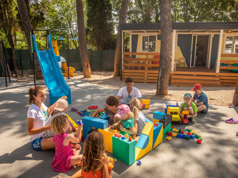 Kinder spielen draußen mit Erwachsenen auf dem Spielplatz von Valamar Camping Ježevac in Kroatien.