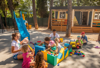 Børn leger udendørs med voksne på Valamar Camping Ježevac, en feriepark i Kroatien med legeplads.