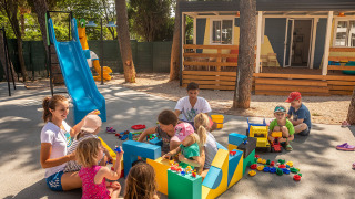 Niños jugando al aire libre con adultos en el parque infantil de Valamar Camping Ježevac en Croacia.