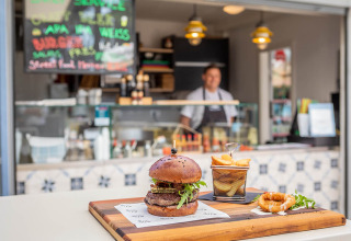 Un succoso hamburger con patatine servito su un tagliere davanti a uno stand al Valamar Camping Ježevac, Croazia.