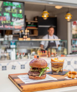 A juicy burger with fries on a wooden board served at a food stall in Valamar Camping Ježevac, Croatia.