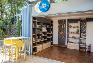 Modern outdoor wine shop at Valamar Camping Ježevac, Croatia, with wooden shelves and tasting table.