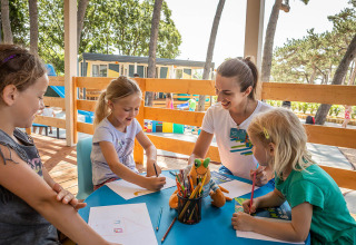 Bambini e un'animatrice fanno attività creative a un tavolo all'aperto al Valamar Camping Ježevac, Croazia.