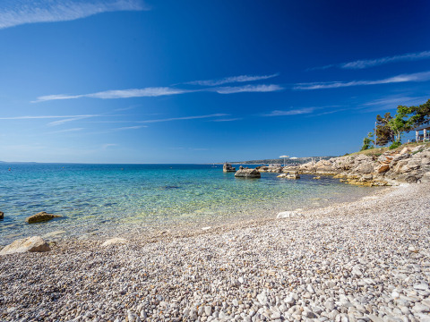 Kiezelstrand met helderblauw water en een zonnige lucht bij Valamar Camping Ježevac, Kroatië, zomerdag.