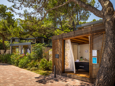 Valamar Camping Ježevac holiday park in Croatia, featuring modern wooden cabins shaded by lush green trees.
