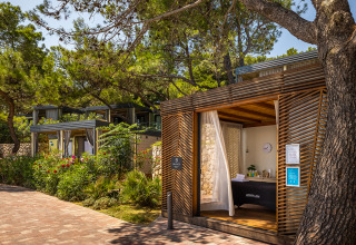 Ferieresort i Valamar Camping Ježevac, Kroatien, med moderne træhytter omgivet af grønne træer og blomster.