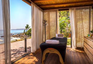 Lys massagekabine med gardiner, wellnessbænk og udsigt over havet på Valamar Camping Ježevac i Kroatien.