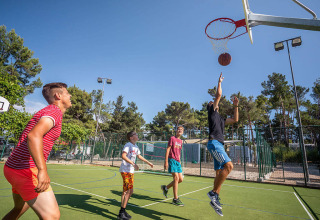 Vier Personen spielen Basketball im Freien bei Valamar Camping Ježevac in Kroatien unter blauem Himmel.