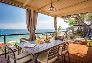 Udsigt fra overdækket terrasse med spisebord og havudsigt i Valamar Camping Ježevac, Kroatien.