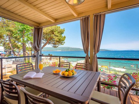 Terrazza coperta con tavolo, sedie e vista mare al Valamar Camping Ježevac, Croazia.