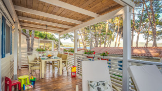 Terrazza coperta all'aperto del lodge Ježevac Home con vista mare, tavolo da pranzo, lettini e giocattoli.