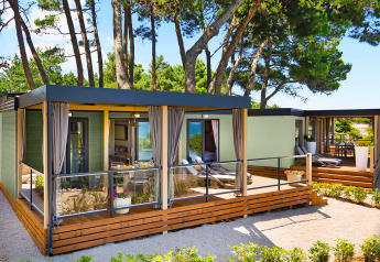 Moderne Lungomare Home lodge med træterrasse omkranset af fyrretræer i et roligt naturområde.
