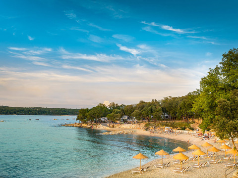 Spiaggia con lettini e ombrelloni al Valamar Camping Istra, un villaggio turistico in Istria, Croazia.