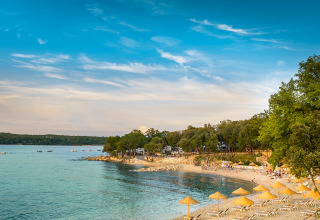 Spiaggia con lettini e ombrelloni al Valamar Camping Istra, un villaggio turistico in Istria, Croazia.