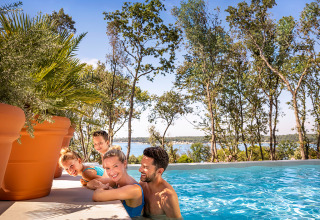 Familie nyder poolen i Valamar Camping Istra, Istrien, Kroatien med udsigt over sø og træer.