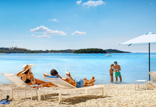 Vacaciones en Valamar Camping Istra en Istria, Croacia, con familias relajándose en tumbonas junto a la playa.