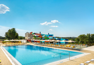 Swimmingpool og farverige vandrutsjebaner under en klar blå himmel ved Valamar Camping Istra i Kroatien.