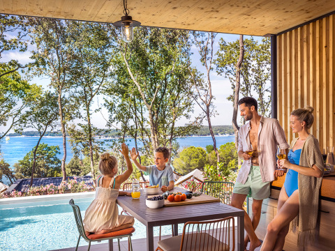 Familie geniet aan het zwembad met uitzicht op zee bij Valamar Camping Istra vakantiepark in Istrië, Kroatië.