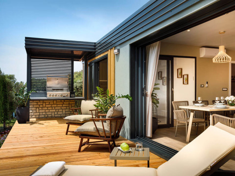 Moderne vakantieveranda met lounge, barbecue en toegang tot de eetkamer in Istrië, Kroatië.