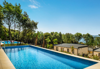 Piscina con vistas a cabañas y naturaleza en Valamar Camping Istra, parque vacacional en Istria, Croacia.