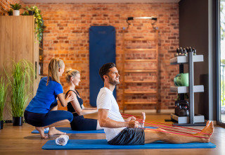 Mensen doen fysiotherapie-oefeningen met elastische banden in de fitness van Valamar Camping Istra, Kroatië.