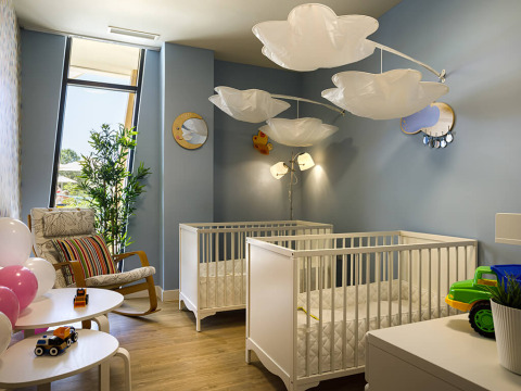 Modern nursery room with two white cribs, cloud-shaped lamps, and toys at Valamar Camping Istra in Croatia.